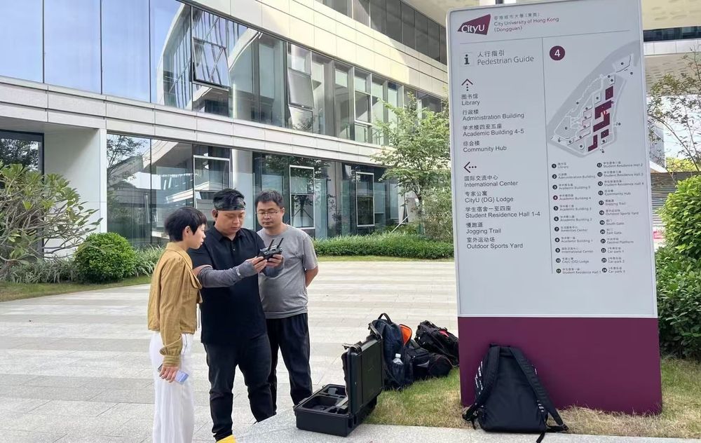 室外航拍准备中工作人员查看遥控器与设备箱